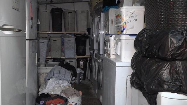 חדר מזוהם עם מכונות כביסה אינסופית ומדפים המעידים על כמות העצומה של הנשים הנמצאות במקום המזעזע 